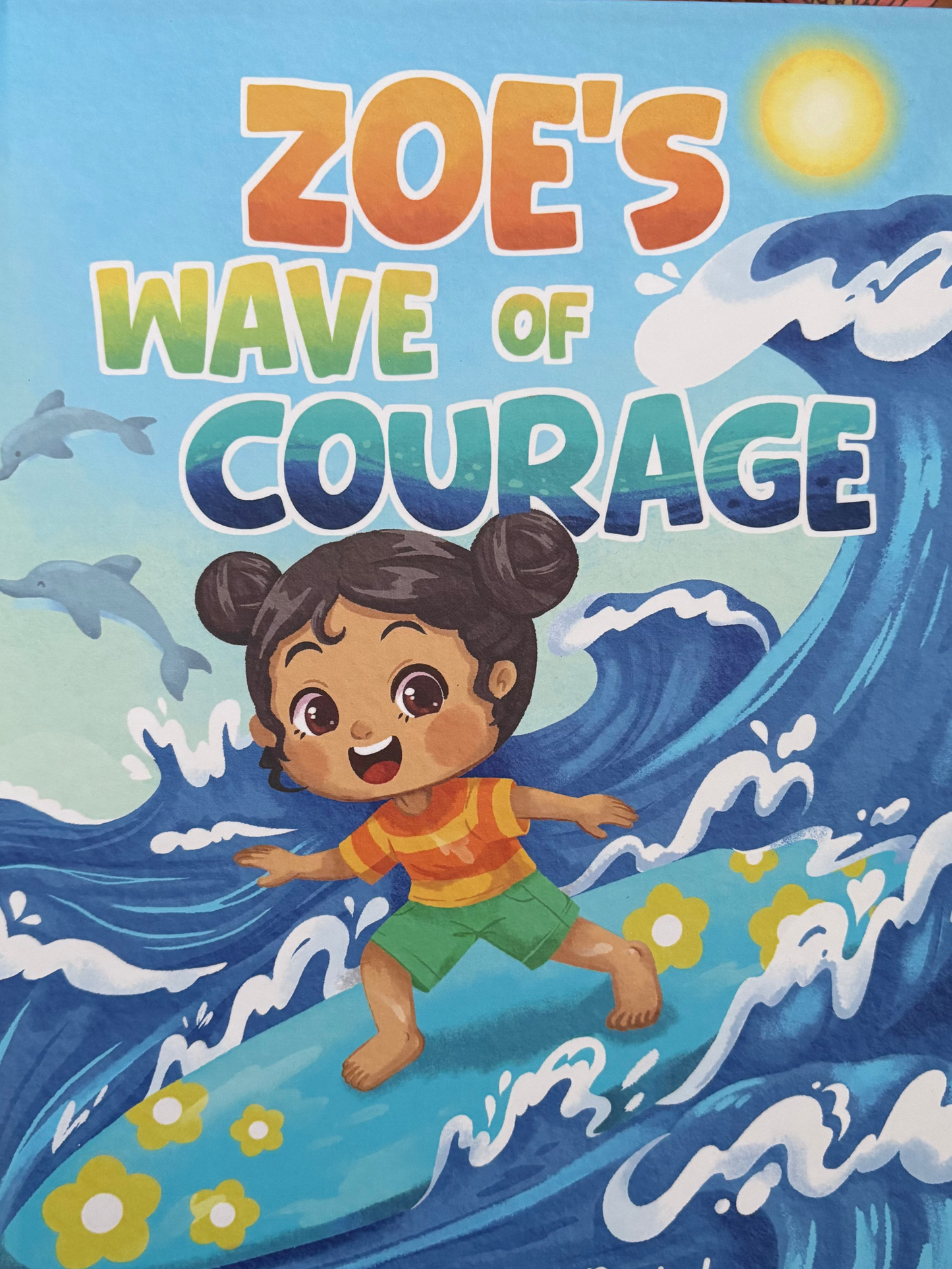 Book titled 'Zoe's Wave of Courage' with a child on a wave illustration on a floral background.