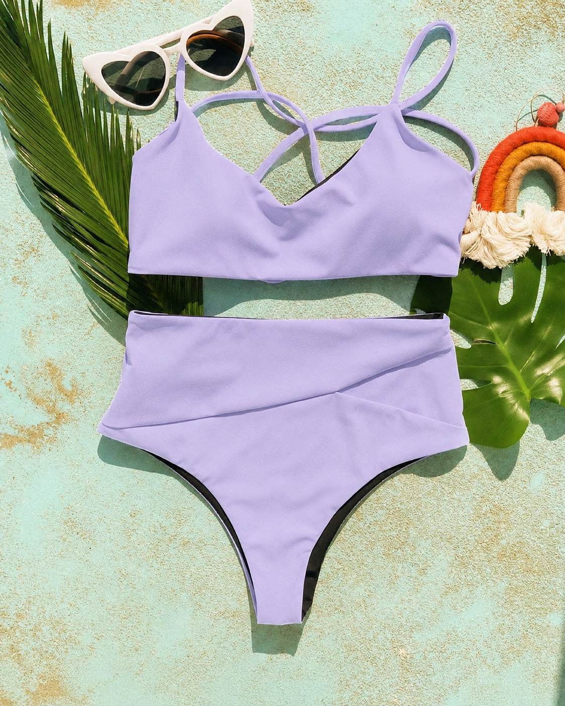Flat-lay of a lavender bralette top and high-waist bikini bottoms with heart sunglasses, the Jazzy bottoms.